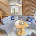 Wohnzimmer mit grauem Sofa, Holztisch und Treppenhaus.