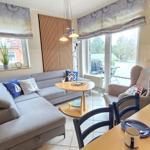 Wohnzimmer mit Sofa, Esstisch und Küchenbereich. Durchgang zur Terrasse mit Sitzgelegenheit.