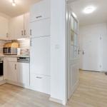 Küche mit integriertem Backofen und Mikrowelle. Flur mit Schrank und Tür.