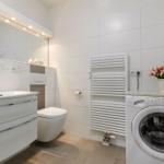 Badezimmer mit Waschmaschine, Spiegel und Heizkörper.