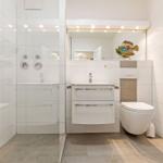 Badezimmer mit Dusche, Waschbecken und Toilette. Wandfliesen und moderne Einrichtung.