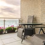 Terrasse mit Sitzgruppe, Blumen und Meerblick.