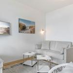 Wohnzimmer mit Sofa, Fernseher und Küchenbereich