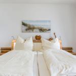 Zimmer mit Doppelbett, Holzkopfteil und Wandbildern