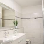 Badezimmer mit Dusche, Waschbecken und Spiegel.