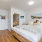 Schlafzimmer mit Doppelbett, Holzboden und Wandbildern