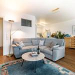 Wohnzimmer mit grauem Sofa, runden Tisch und Holzboden.