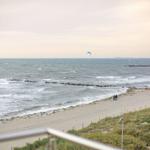 Meerstrand mit Kitesurfer und zwei Personen spazieren