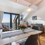 Wohnbereich mit Esstisch, Sofa und Balkontür zum Meer.