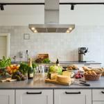 Moderne Küche mit Arbeitsplatte, Obst, Gemüse und Käse. Hintergrund: weiße Fliesen und Küchenspüle.