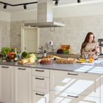 Küche mit Arbeitsplatte, Obst, Gemüse und Frau mit Smartphone.