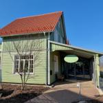 Grünes Haus mit rotem Dach und Eingangsbereich unter Vordach.