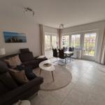 Wohn- und Essbereich mit Sofa, Tisch und Blick auf Garten.