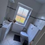 Badezimmer mit Toilette, Waschbecken und Fenster mit getöntem Glas.