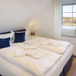 Schlafzimmer mit Doppelbett, Fensterblick und gefalteten Handtüchern.