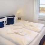 Schlafzimmer mit Doppelbett, Fensterblick und gefalteten Handtüchern.