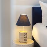 Nachttisch mit Lampe neben Bett mit Kissen