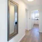 Flur mit Spiegel, Holzboden und Blick in Küche und Schlafzimmer.