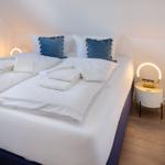 Schlafzimmer mit Doppelbett, blauen Kissen und runden Nachttischen mit Beleuchtung.