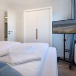 Schlafzimmer mit Bett, TV und Garderobe.