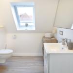 Dusche, Waschbecken und Toilette unter Dachschrägen mit Fenster.