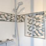 Duschkabine mit Glaswand, Mosaikfliesen und Duschbrause