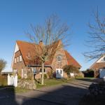 Haus mit rotem Dach, weißer Tür und Garten