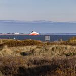 Rotes Schiff auf dem Wasser, umgeben von Dünen und Vegetation.