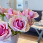 Ein Strauß rosa Rosen steht auf einem Tisch vor einem Sofa.