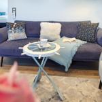 Ein Wohnzimmer mit blauem Sofa, Kissen und einem Tisch mit Ruder.