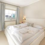 Schlafzimmer mit Doppelbett, Fenster und Nachttisch