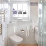 Badezimmer mit Dusche, Toilette und Fenster. Weiße Fliesen und Handtücher.