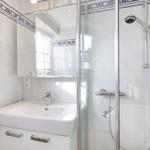 Badezimmer mit Dusche, Waschbecken und Spiegel