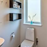 Badezimmer mit Toilette, Waschbecken und Dusche. Fenster mit Blumenvase.