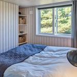 Schlafzimmer mit Bett, Fenster und Wandlampe.