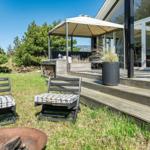 Außenbereich mit Terrasse, Sitzgelegenheiten und Feuerkorb. Moderne Architektur mit Glasfassade.
