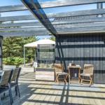 Terrasse mit Tisch, Stühlen und Pavillon. Holzwand und Glastüren sind sichtbar.