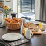 Frühstückstablett mit Brötchen, Milch, Saft und Kaffeekanne.