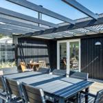 Terrasse mit Tisch, Stühlen und Pavillon. Durchgehendes Glasfenster zum Innenraum.