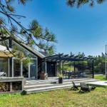 Moderne Villa mit Terrasse, Grillplatz und Garten. Holzstapel und Sitzgelegenheiten.