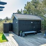 Schwarze Sauna mit Holzterrasse, Liegestühle und Pflanzen im Garten.