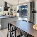 Moderne Küche mit Essbereich und rotem Sessel. Draußen ist eine Terrasse.