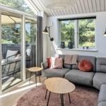Wohnzimmer mit grauem Sofa, runden Tischen und Blick auf Balkon.