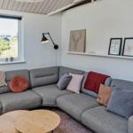 Ein Raum mit grauem Ecksofa, Holztisch und Fensterblick auf Grün.