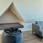 Wohnzimmer mit Sofa, Sitzbank unter Dachschräge und Sitzhocker.