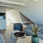 Wohnzimmer mit Sofa, Beistelltisch und Fernseher unter Dachschrägen.