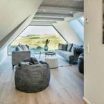 Wohnzimmer mit Sitzgelegenheiten und großem Fenster zur Landschaft