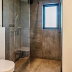 Badezimmer mit Dusche, Toilette und Waschtisch. Fenster mit blauem Rahmen.