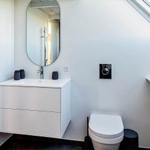 Badezimmer mit Waschbecken, Toilette und Dachschräge