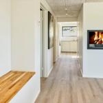 Hallenraum mit integriertem Kamin und Holzboden. Links Sitzbank, rechts Treppe.